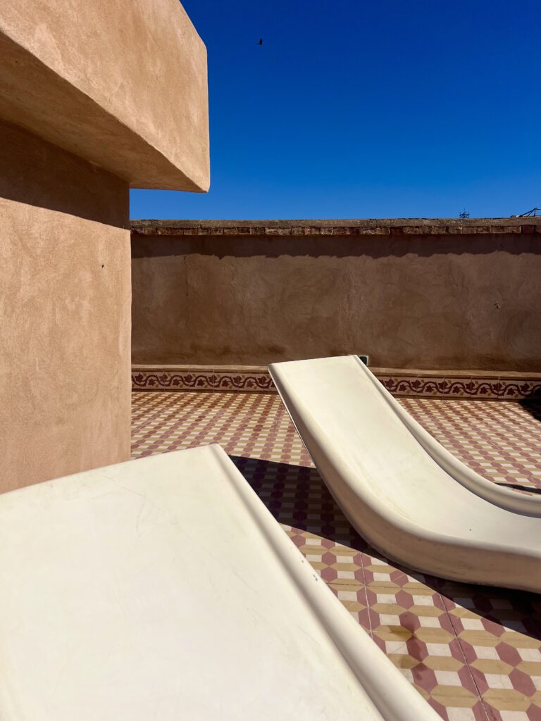 Spacious private rooftop terrace at Dar Tizwa with sun loungers, outdoor dining and panoramic views across Marrakech.